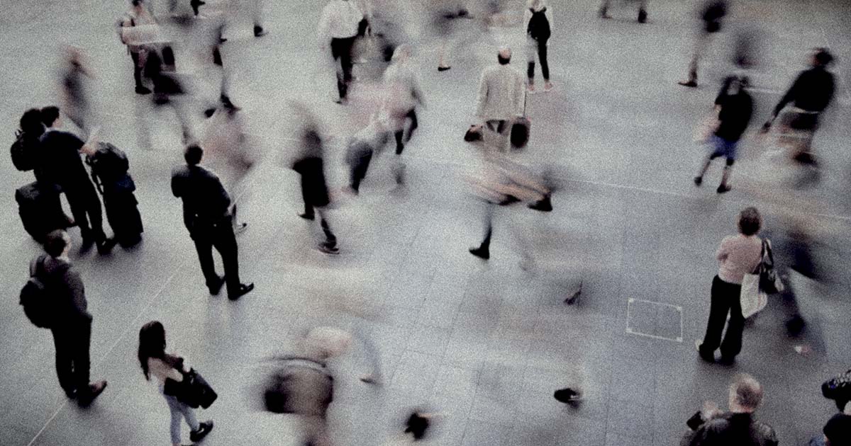 An aerial timelapse photo of a busy crosswalk with blurry, fast-moving people