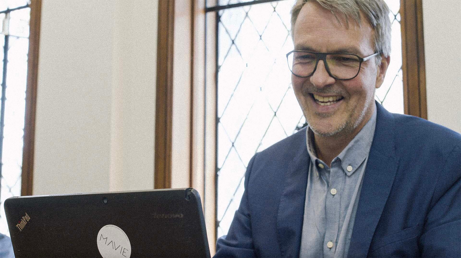 Carsten Frien smiling while using a laptop in Roqad office