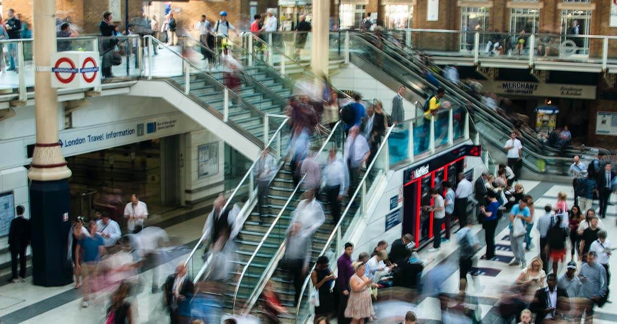 A timelapse photo of a busy airport or bus terminal with fast moving people appearing as a blur