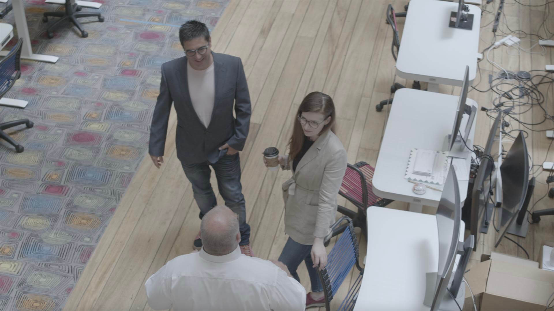 Overhead photo of Ollie James, Jennifer Schiffman, and Kevin Mullen from Roqad chatting in the office